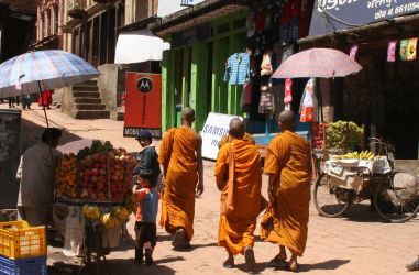 Monks on cobbled streets walking past fruit vendors