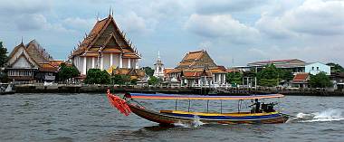 Colorful longtail blasting past a beautiful Wat in Bangkok