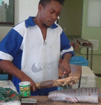 Chopping fish steaks with a machete & a wooden stick