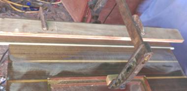 Houa gluing a piece of teak & an ash strip into a floorboard