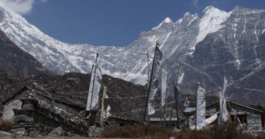 Prayer flags and mani walls under the towering peaks
