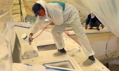 Mike spraying gelcoat inside a plastic tent of masking material